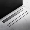 Two linear shower drains are placed on a marble-tiled floor, with a dark, solid surface in the background. Náhľad obrázku produktu
