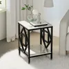 A small side table with a marble-like top and a black geometric frame, placed on a fluffy white rug next to a sofa. A vase with greenery and a small figurine are on top of the table. Produktbild-Vorschau