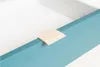 A close-up shot of a teal-colored furniture piece with a small wooden accent piece on its edge. Produktbild-Vorschau