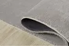 A close-up view of a gray rug, showing its texture and the underside with a non-slip pattern. Produktbild-Vorschau