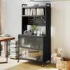 A tall gray cabinet with shelves and mesh doors, placed in a room with a wooden table and stacks of books. Náhľad obrázku produktu