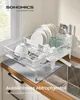 A white dish drying rack with plates, bowls, and glasses is placed on a kitchen counter next to a sink. Water is draining from the rack into the sink. Produktbild-Vorschau