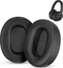 Two black ear pads for headphones are shown in the foreground, with a pair of black headphones in the background. Podgląd zdjęcia produktu