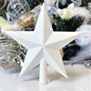 A white glitter star Christmas tree topper with a conical base, surrounded by other Christmas tree decorations. Anteprima dell’immagine prodotto