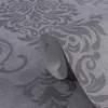 A close-up of a roll of grey wallpaper with a damask pattern. Produktbild-Vorschau