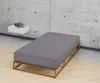 A bed frame with a mattress in a minimalist room with a concrete wall. Produktbild-Vorschau