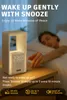 A person sleeping in bed next to a bedside table with a digital alarm clock and lamp. Produktbild-Vorschau