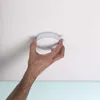 A hand is installing a smoke detector on a white ceiling. Náhľad obrázku produktu