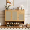 A wooden shoe cabinet with rattan doors and a shelf for shoes, decorated with a vase of flowers, a lamp, and a framed picture. Produktbild-Vorschau
