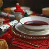 A festive table setting with a bowl of red soup, crackers, and bread. Produktbild-Vorschau