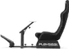 A black gaming chair with a steering wheel mount and pedals, shown from the side against a white background. Produktbild-Vorschau