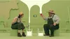 Two people dressed as farmers are playing a game that simulates milking a cow. Produktbild-Vorschau