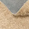 A close-up view of the underside and pile of a beige shaggy rug. Produktbild-Vorschau