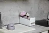 A kitchen sink area with a decorative organizer filled with flowers and towels, next to a stovetop. Produktbild-Vorschau