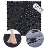 A black anti-slip bath mat with a pebble-like texture, shown with a close-up of feet on the mat and a close-up of the suction cups on the underside. Produktbild-Vorschau