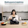A young woman using a food slicer in a modern kitchen. Podgląd zdjęcia produktu