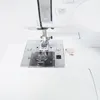 A close-up view of the needle plate and presser foot of a white sewing machine. Produktbild-Vorschau