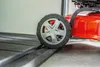 A close-up view of a red lawnmower wheel on a black ramp. Podgląd zdjęcia produktu