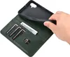 A hand is holding a dark green leather wallet case for a smartphone, showing the card slots and a bill inside. Produktbild-Vorschau