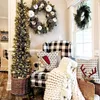 A cozy Christmas-themed living room corner with a decorated tree, wreaths, and festive pillows on a chair. Produktbild-Vorschau