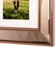 A close-up of a copper-colored picture frame with a mirrored effect, showing a portion of a photo with a person and grass. Podgląd zdjęcia produktu