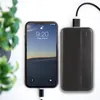 A black smartphone is charging from a black power bank. A green plant is in the background. Produktbild-Vorschau