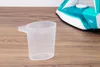 A measuring cup is in the foreground, with an iron in the background. Produktbild-Vorschau
