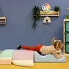 A young child is playing on a set of soft play blocks in a room with blue walls. Produktbild-Vorschau