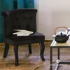 A black velvet chair with books on it, next to a coffee table with a teapot. Produktbild-Vorschau