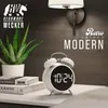 A white digital alarm clock is placed on a nightstand next to a potted plant and books, with a wall lamp in the background. Anteprima dell’immagine prodotto