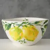 A white ceramic bowl with a hand-painted lemon and leaf design. Anteprima dell’immagine prodotto