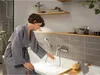 A woman is running the water into a bathtub in a modern bathroom. Anteprima dell’immagine prodotto