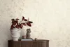 A close-up of a textured wallpaper with a vase of red leaves and a small statue on a wooden cabinet. Produktbild-Vorschau