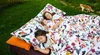 Three children are sleeping on a large, colorful duvet outdoors on the grass, with a cat in the background. Produktbild-Vorschau