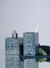 A soap dispenser and toothbrush holder set on a reflective surface with a light gray background. Náhled obrázku produktu