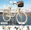 A cream-colored women's bicycle with a brown basket is parked on a road with a scenic background. Produktbild-Vorschau