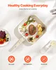 A white grill pan filled with food, placed on a white surface with a fruit salad in a bowl to the left and a glass of water to the right. Náhled obrázku produktu