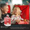 A grandmother and granddaughter are sitting together, smiling, with Christmas decorations in the background. A wrapped gift is in the foreground. Produktbild-Vorschau