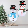 Two felt snowman crafts are displayed on a wall next to a decorated Christmas tree, with pillows on the floor in the foreground. Náhľad obrázku produktu