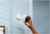 A hand is holding a white Google Nest Cam, about to attach it to a white magnetic mount on a light blue wall. Voir les images du produit