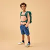 A young boy wearing a backpack and school uniform stands against a plain background. Anteprima dell’immagine prodotto