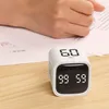 A person's hand is writing on a document next to a white cube timer on a wooden desk. Produktbild-Vorschau