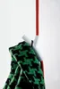 A white hook with a red cord and a green and black patterned scarf hanging from it, against a white background. Anteprima dell’immagine prodotto