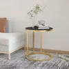 A round side table with a black top and gold metal frame, placed next to a sofa in a living room setting. Podgląd zdjęcia produktu