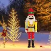 A festive outdoor scene at night, featuring illuminated Christmas decorations including a large nutcracker figure, a light-up tree, and a reindeer. Produktbild-Vorschau