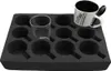 A black foam insert with 12 circular cutouts, designed to hold cups or glasses. A clear glass and a white mug with black text are placed in the insert. Podgląd zdjęcia produktu