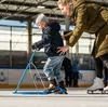 A child is learning to ice skate with the help of an adult. Produktbild-Vorschau