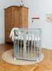 A nursery room with a crib, a wooden wardrobe, and a rug. Produktbild-Vorschau