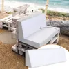 A white foam cushion is placed on a stack of wooden pallets on a beach, with the ocean in the background. Produktbild-Vorschau
