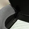 A close-up view of the interior of a storage bench, showing a black metal hinge mechanism with a spring, attached to the dark gray fabric interior of the bench lid. A white quilted fabric is visible at the bottom of the frame. Anteprima dell’immagine prodotto